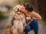 a woman kissing her dog on the cheek